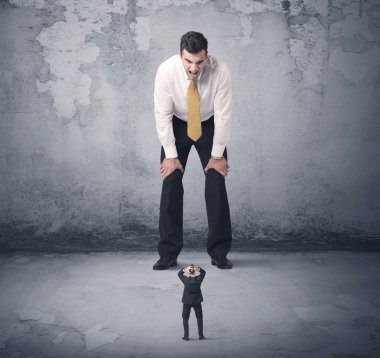 Büyük işletme zorbası küçük iş arkadaşına bakıyor.