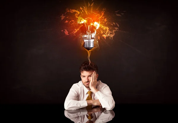 Businessman sitting under a blowing idea bulb — Stock Photo, Image