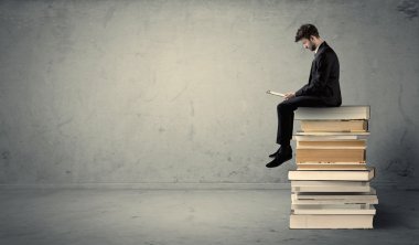Adam kitaplar üzerinde oturan dizüstü bilgisayar ile