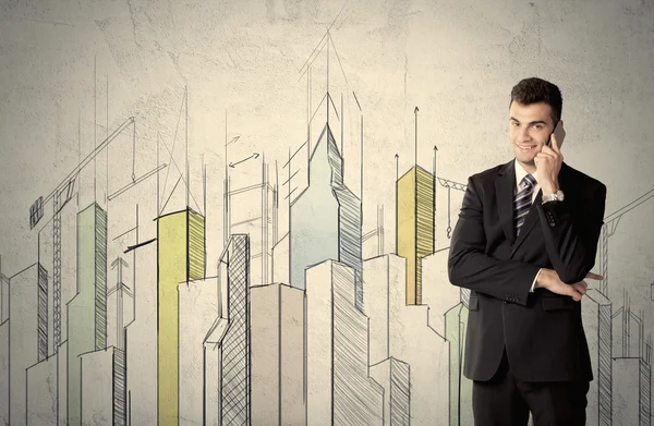 Businessman standing with drawn cityscape — Stock Photo, Image