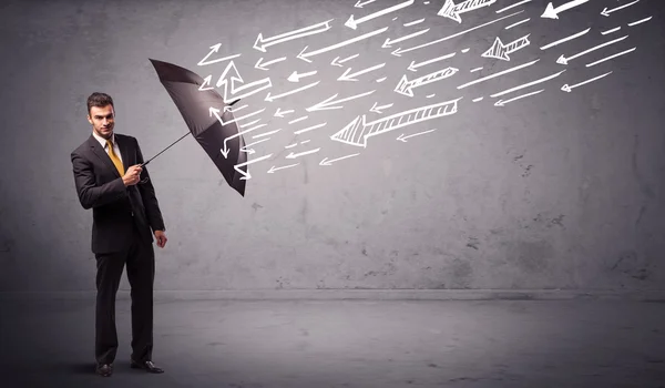 Homem de negócios de pé com guarda-chuva e flechas desenhadas batendo nele — Fotografia de Stock