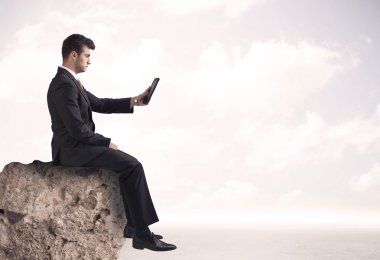 İş adamı taşın üstünde oturuyor.