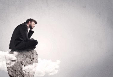 Ofis çalışanı kayanın tepesinde oturuyor.