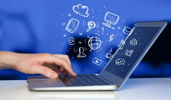 Hand writing on notebook computer with media icons — Stock Photo, Image