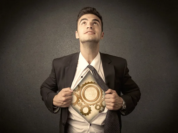 Businessman tearing shirt off and machine cog wheel shows