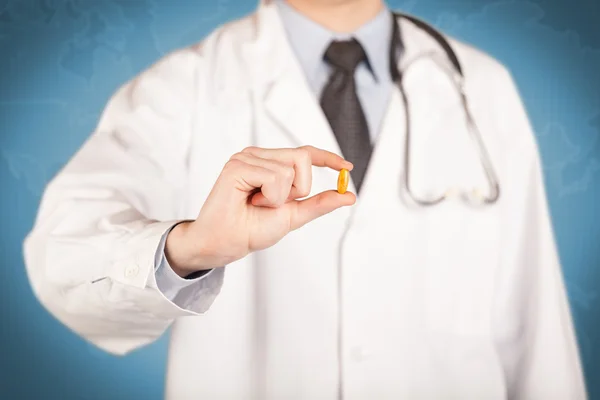 Médecin en blanc tenant une pilule — Photo