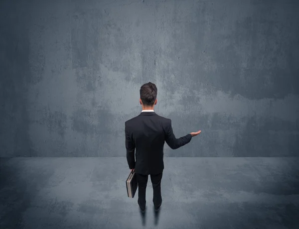 Businessman standing in front of urban wall — Stock Photo, Image