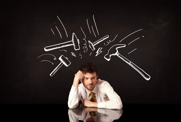 Depressed businessman sitting under hammer marks — Stock Photo, Image