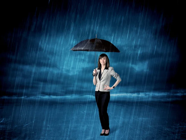 Business woman standing in rain with an umbrella — Stock Photo, Image