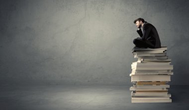 Şık erkek kitaplar üzerinde oturmuş