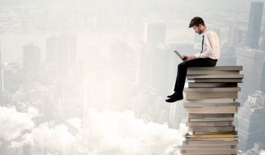 Şehirde kitap yığınının üzerinde oturan bir öğrenci