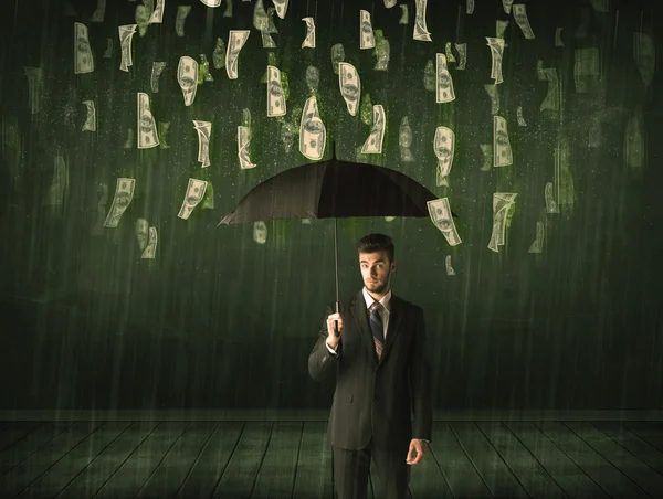 Businessman standing with umbrella in dollar bill rain concept — Stock Photo, Image