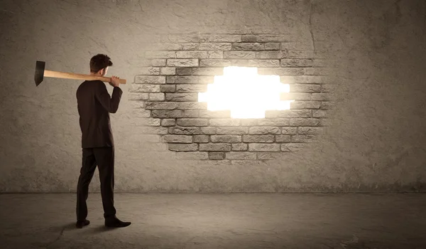 Business man hitting brick wall with hammer and opening a hole — Stock Photo, Image