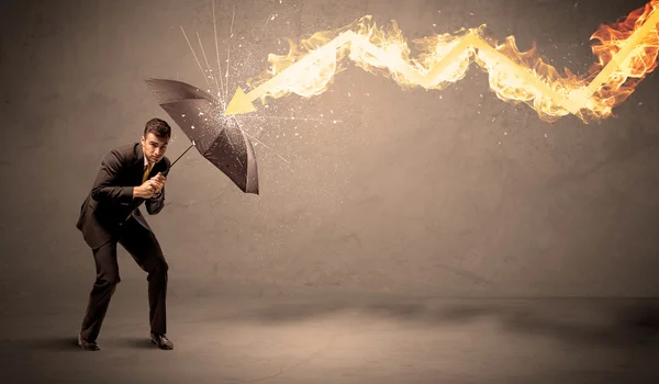 Homme d'affaires se défendant d'une flèche de feu avec un parapluie — Photo