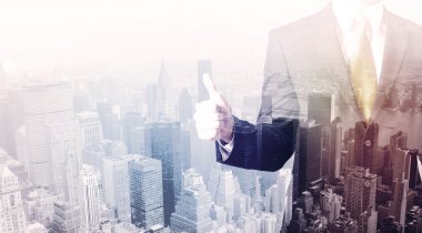 İş adamı çatıda duruyor ve arka planda şehir var.