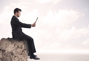 İş adamı taşın üstünde oturuyor.