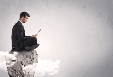 Ofis çalışanı kayanın tepesinde oturuyor.