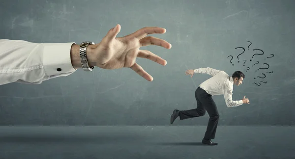 Businessman running away from a big hand — Stock Photo, Image