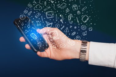 Elle çizilmiş medya simgeleri ve sembolleri ile akıllı telefonu tutmak