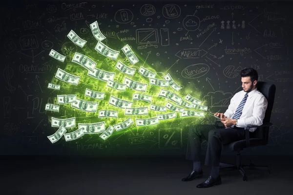 Affärsman som sitter i stol anläggning tablett med dollarn räkningar co — Stockfoto