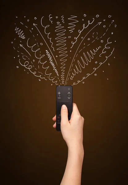 Hand with remote control and curly lines — Stock Photo, Image