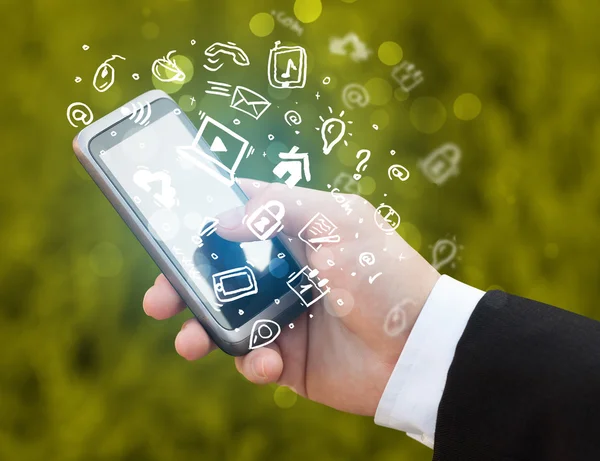 Hand holding smartphone with media icons and symbol — Stock Photo, Image