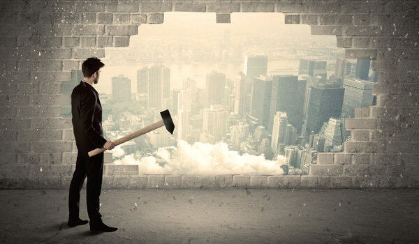 Деловой человек бьет молотком по стене с видом на город