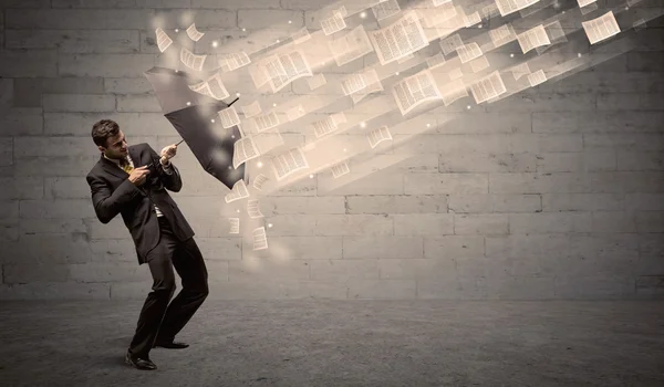 Hombre de negocios protegiendo con paraguas contra viento de papeles — Foto de Stock