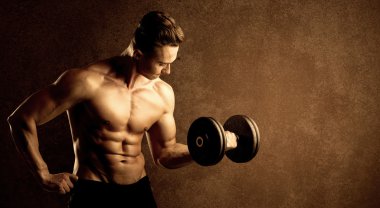 Kas formundaki vücut geliştirici sporcu ağırlık kaldırıyor 