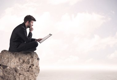 İş adamı taşın üstünde oturuyor.