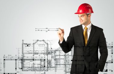 Genç bir mimar ev planı çiziyor.