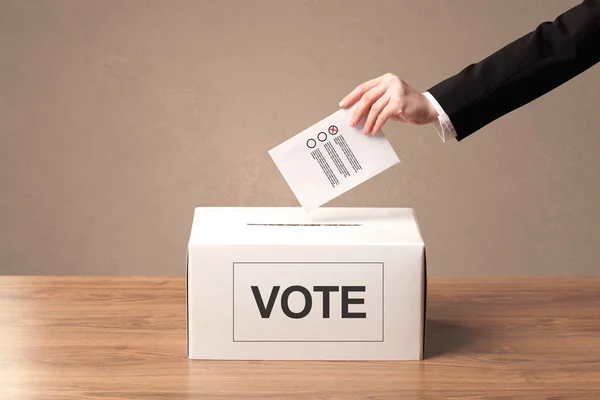 Fechar a mão masculina colocando voto em uma urna — Fotografia de Stock