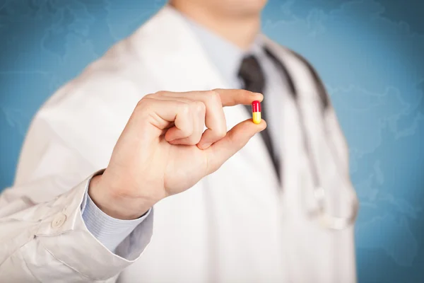 Doctor en blanco sosteniendo una píldora — Foto de Stock