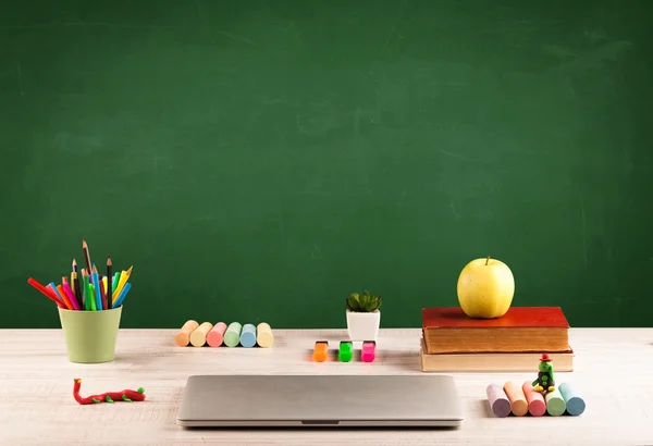 Schoolspullen op bureau met leeg schoolbord — Stockfoto