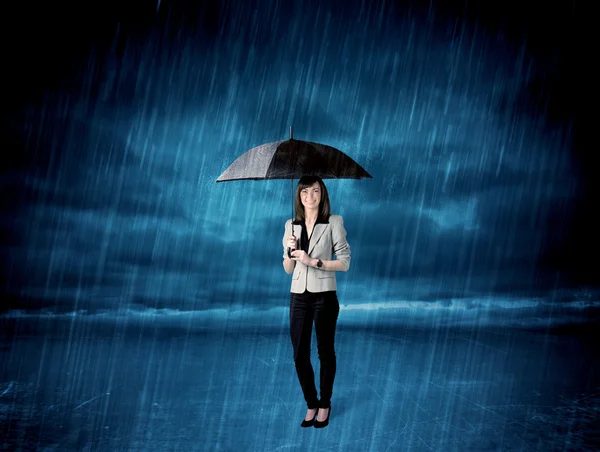 Business woman standing in rain with an umbrella — Stock Photo, Image