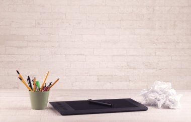 Ofis masası beyaz tuğla duvarla kapanıyor.