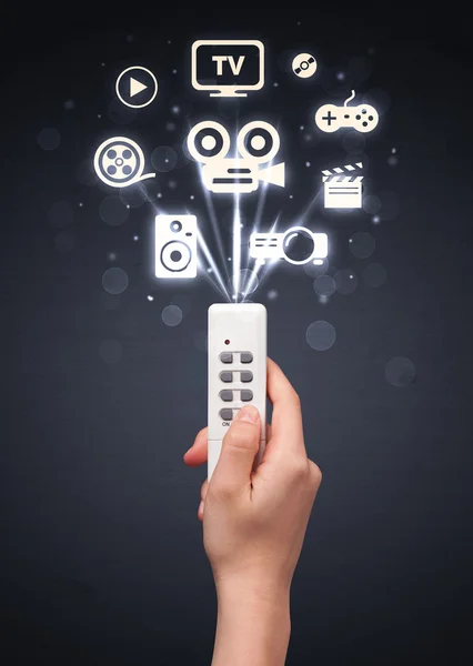 Hand with remote control and media icons — Stock Photo, Image