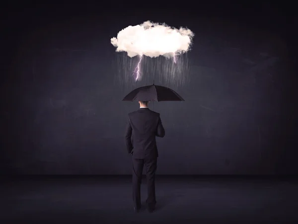 Affärsman står med paraply och lite storm moln Stockfoto