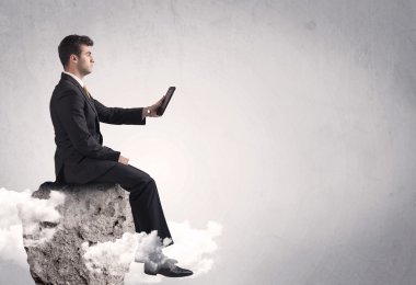 Ofis çalışanı kayanın tepesinde oturuyor.