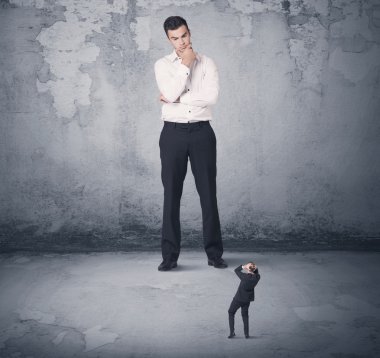 Büyük işletme zorbası küçük iş arkadaşına bakıyor.