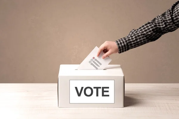 A férfi keze szavazás üzembe a szavazólapon doboz közelről — Stock Fotó