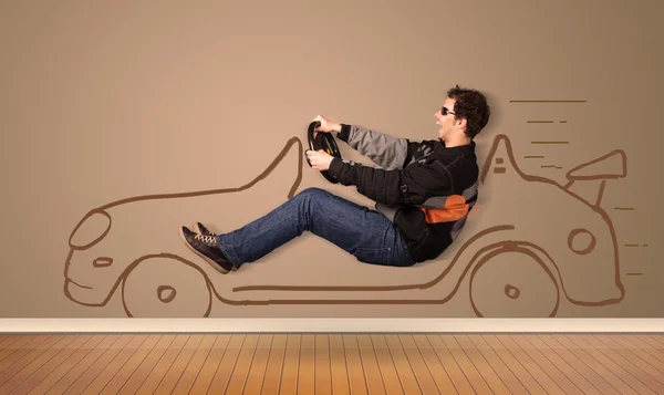 Lykkelig mand kører en håndtegnet bil på væggen - Stock-foto