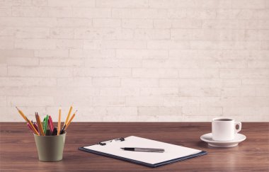 Ofis masası beyaz tuğla duvarla kapanıyor.