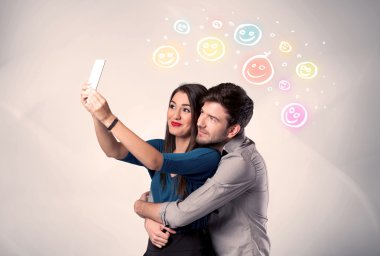 Mutlu çift gülen yüzle selfie çekiyor.