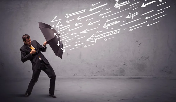 Business man standing with umbrella and drawn arrows hitting him — Stock Photo, Image