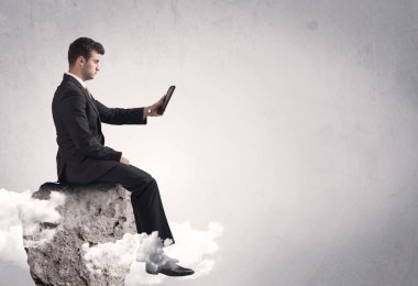 Ofis çalışanı kayanın tepesinde oturuyor.