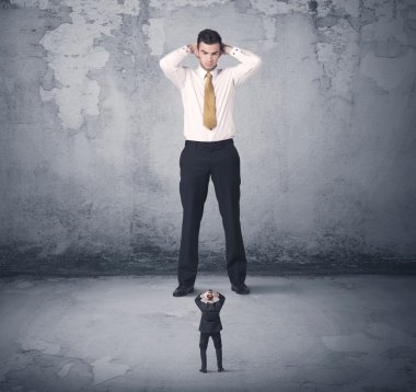 Büyük işletme zorbası küçük iş arkadaşına bakıyor.