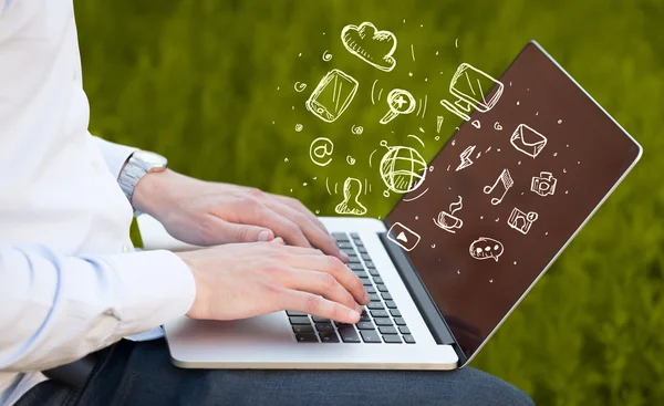 Hand writing on notebook computer with media icons — Stock Photo, Image