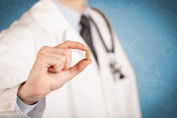 Doctor in white holding a pill — Stock Photo, Image