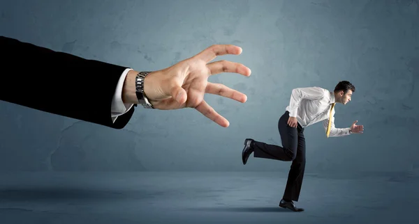 Hombre de negocios huyendo de un concepto de mano enorme — Foto de Stock